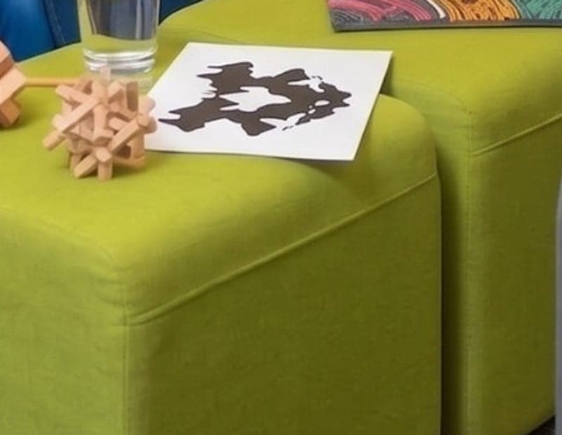 Wooden puzzle blocks and a black-and-white ink-blot card on a lime green ottoman.