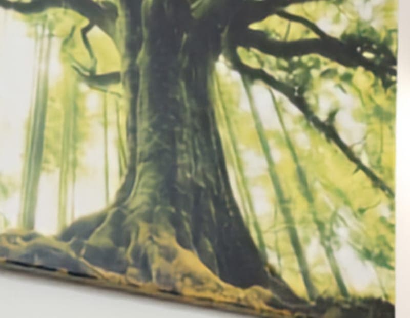 A close view of a canvas print: dark branches against yellow-green light.