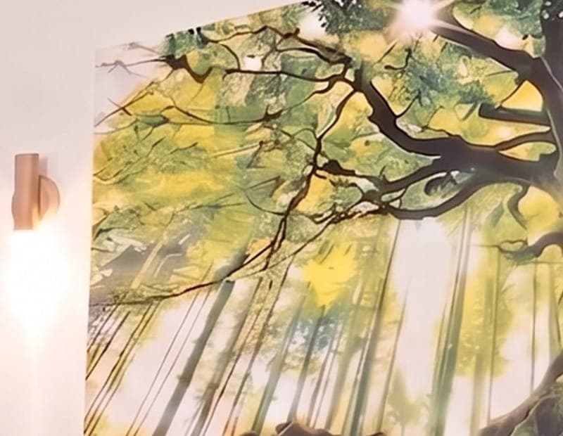 A canvas print of sunlight through the branches of a tree, lit by a small wall lamp.